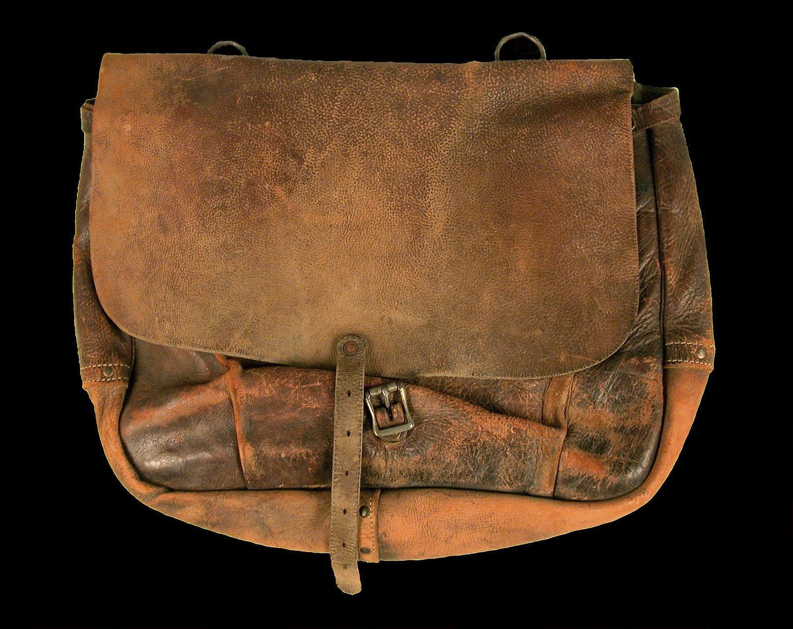 Bolsa aberta sobre a mesa com guarda-chuva, carregador e outros itens de precaução