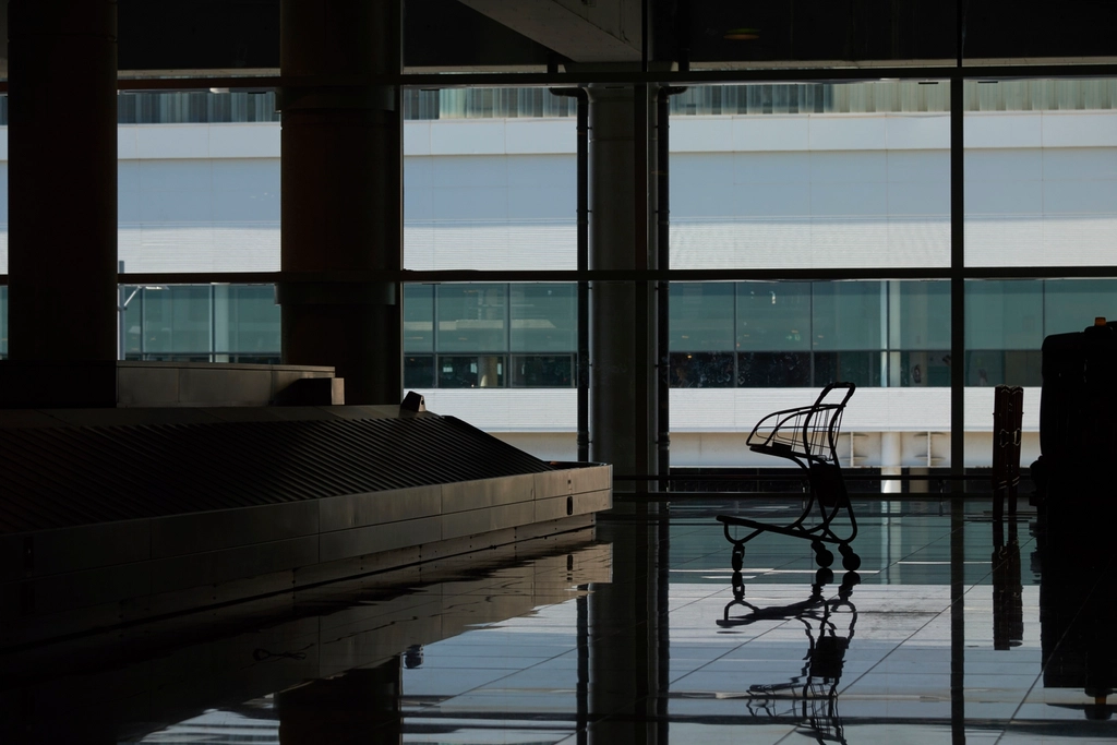 Fileira de cadeiras vazias em um saguão de aeroporto ainda sem movimento
