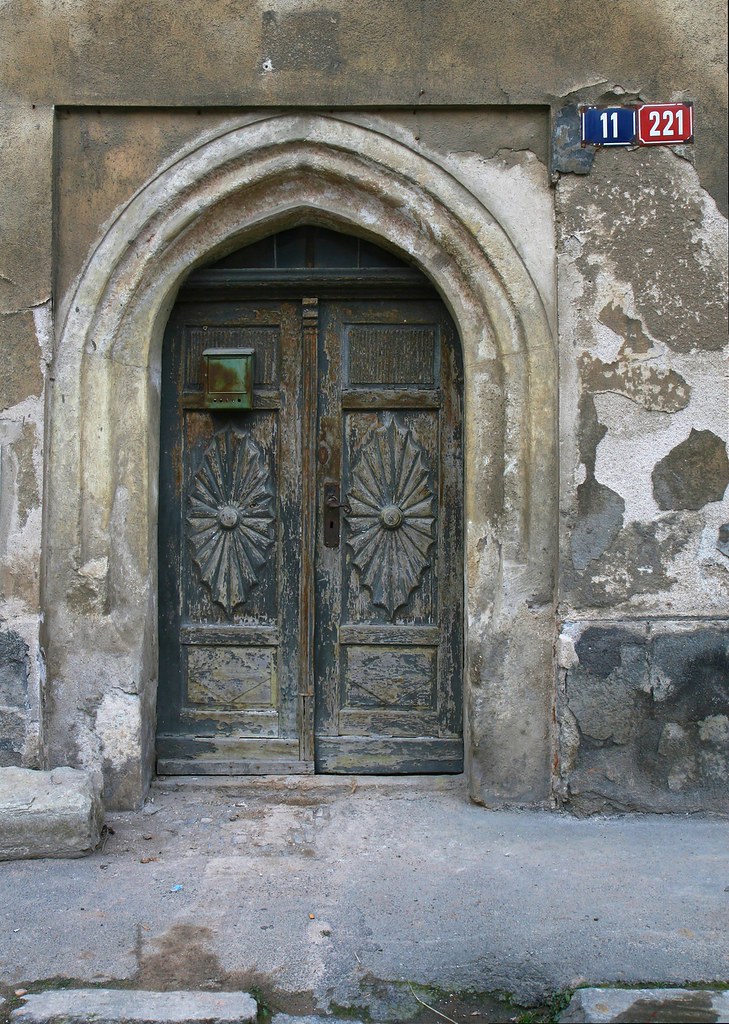Porta antiga e desgastada que evoca a sensação de hesitação e barreira antes de atravessar um limiar, simbolizando bem a