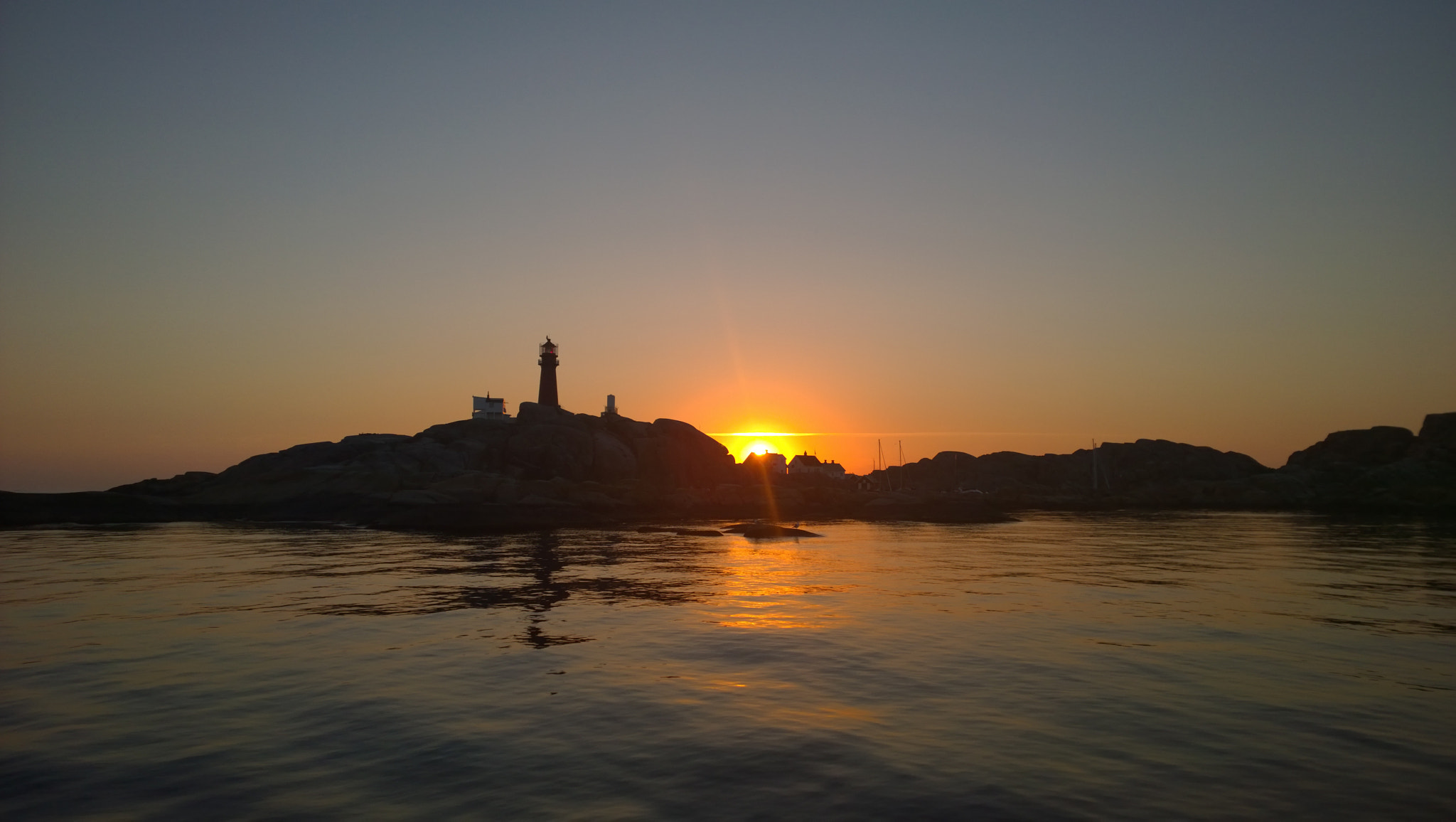 farol sereno à beira de um mar calmo ao pôr do sol