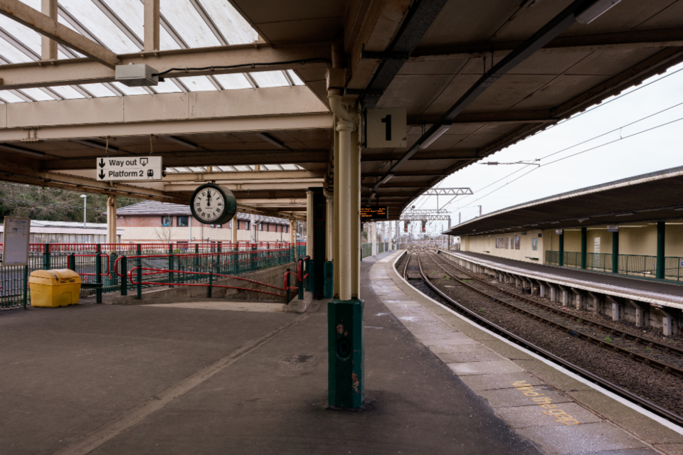 Banco vazio numa plataforma de trem iluminada pela luz da manhã